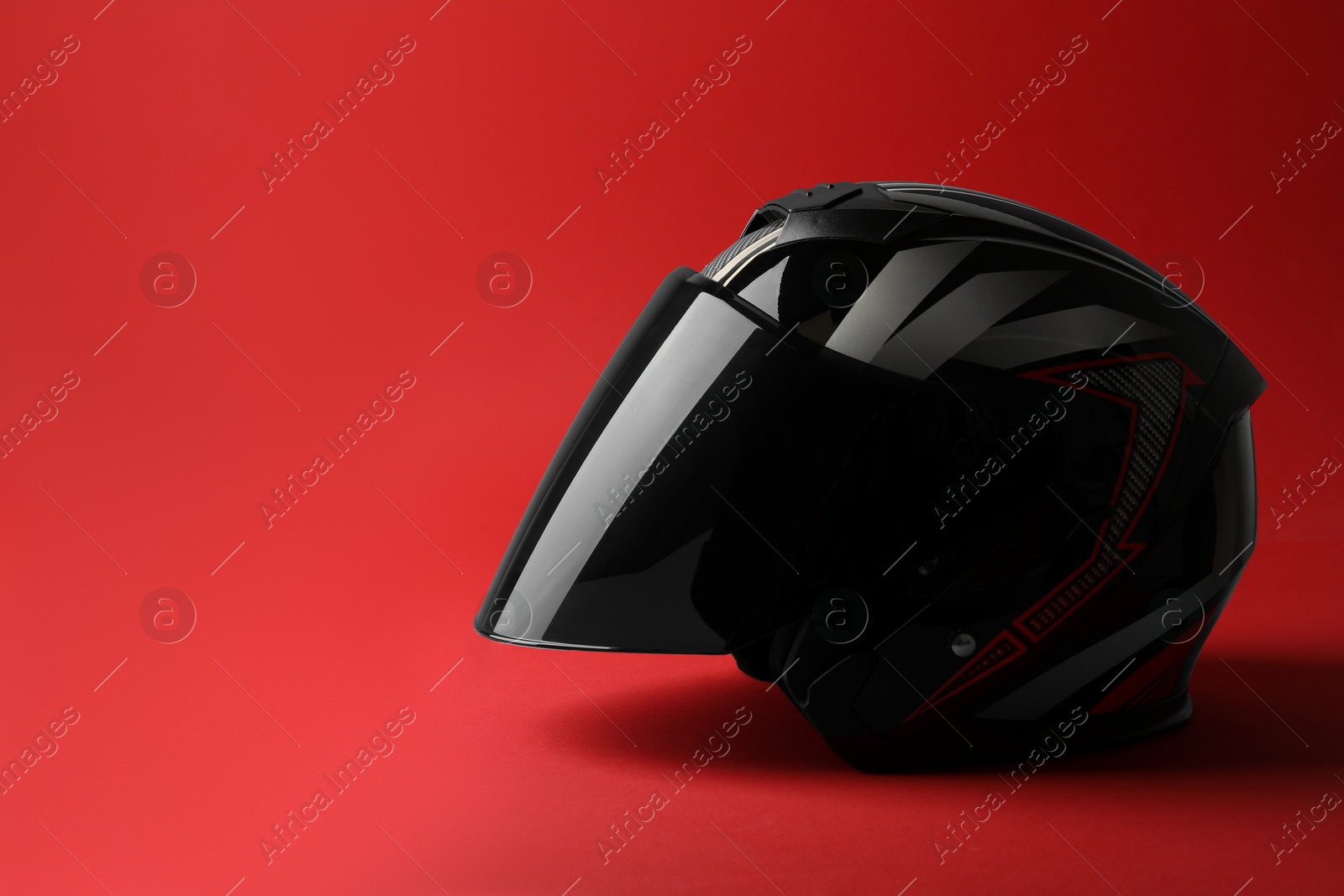 Photo of Modern motorcycle helmet with visor on red background, space for text