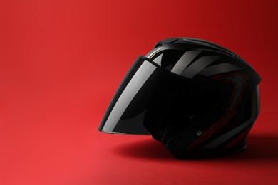 Photo of Modern motorcycle helmet with visor on red background, space for text