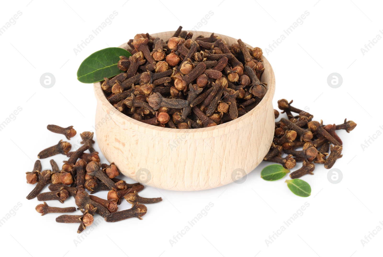 Photo of Dry clove buds in wooden bowl and green leaves on white background. Aromatic spice