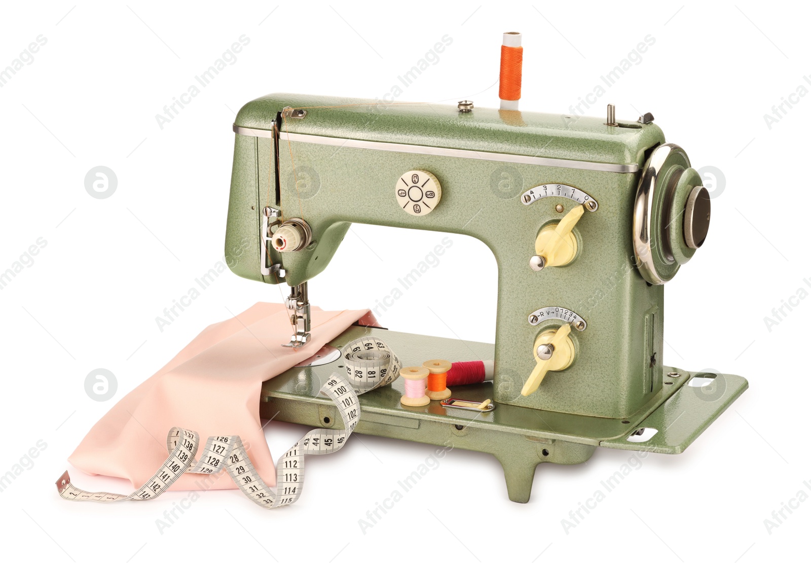 Photo of Sewing machine with pink fabric, measuring tape and spools of threads isolated on white