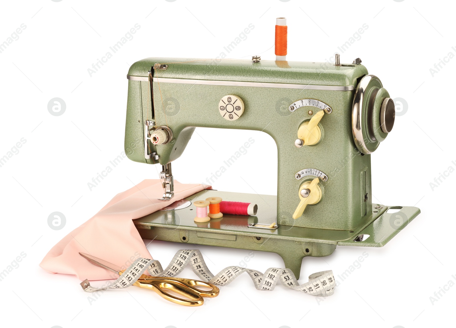 Photo of Sewing machine with pink fabric, measuring tape, scissors and spools of threads isolated on white