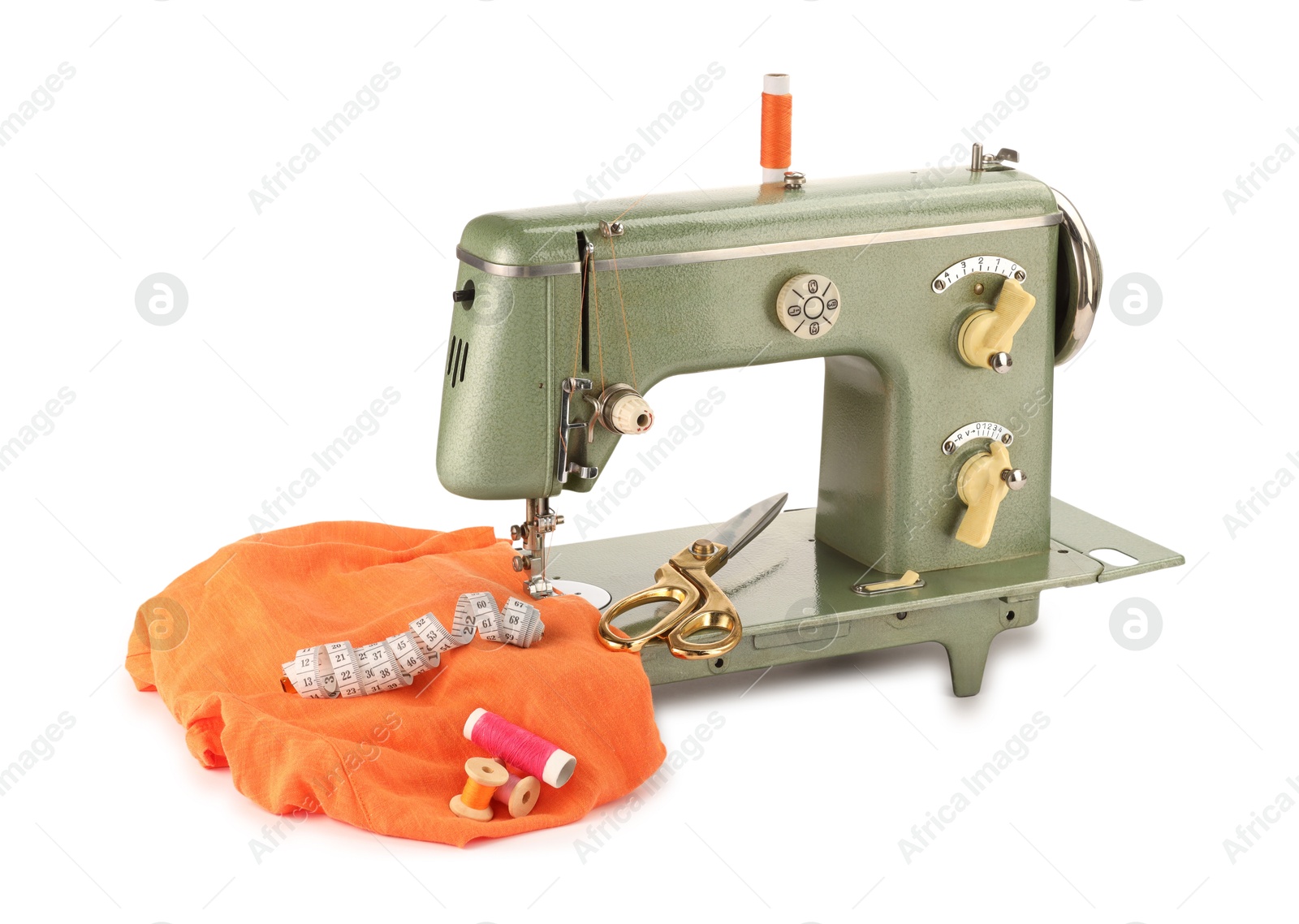 Photo of Sewing machine with orange fabric, measuring tape, scissors and spools of threads isolated on white