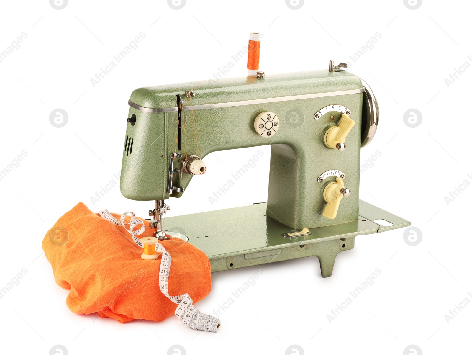 Photo of Sewing machine with orange fabric, measuring tape and spools of threads isolated on white