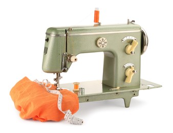 Photo of Sewing machine with orange fabric, measuring tape and spools of threads isolated on white