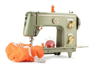 Photo of Sewing machine with orange fabric, measuring tape, pincushion and spools of threads isolated on white