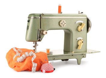 Photo of Sewing machine with orange fabric, measuring tape, pincushion and spools of threads isolated on white