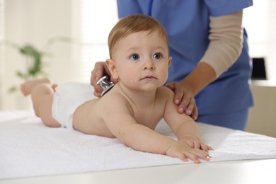 Pediatrician examining little child with stethoscope in clinic, closeup. Checking baby's health