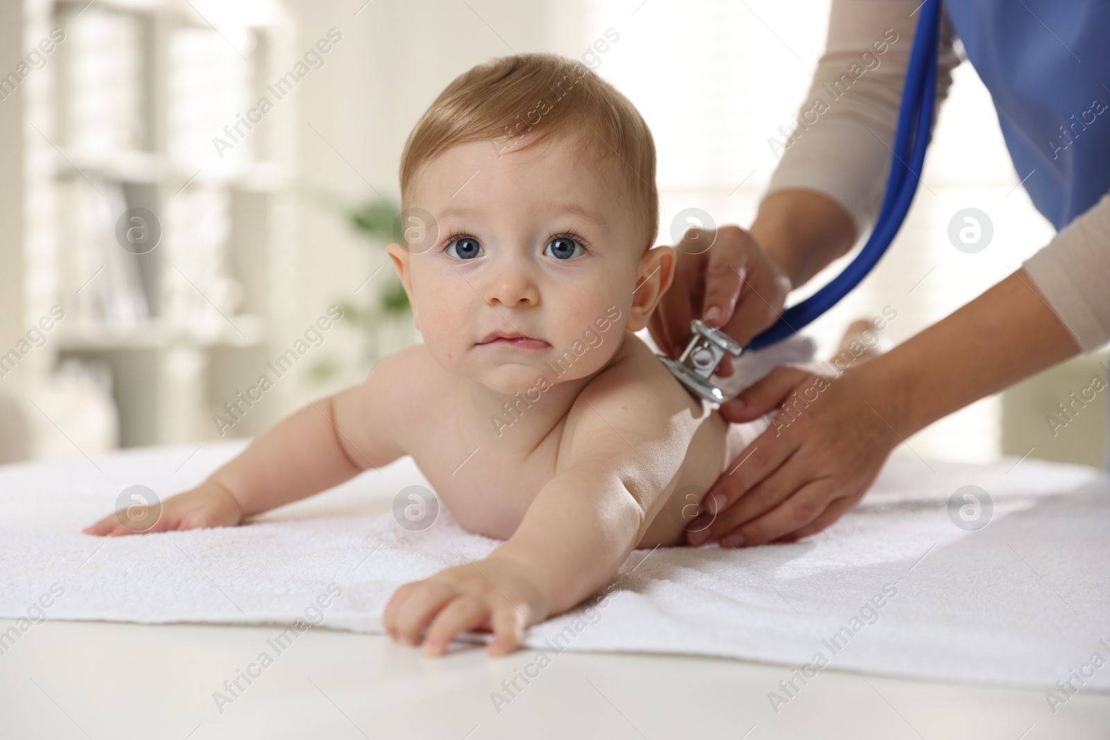 Photo of Pediatrician examining little child with stethoscope in clinic, closeup. Checking baby's health