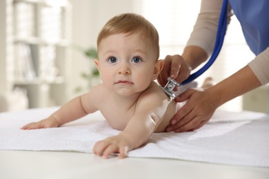 Pediatrician examining little child with stethoscope in clinic, closeup. Checking baby's health