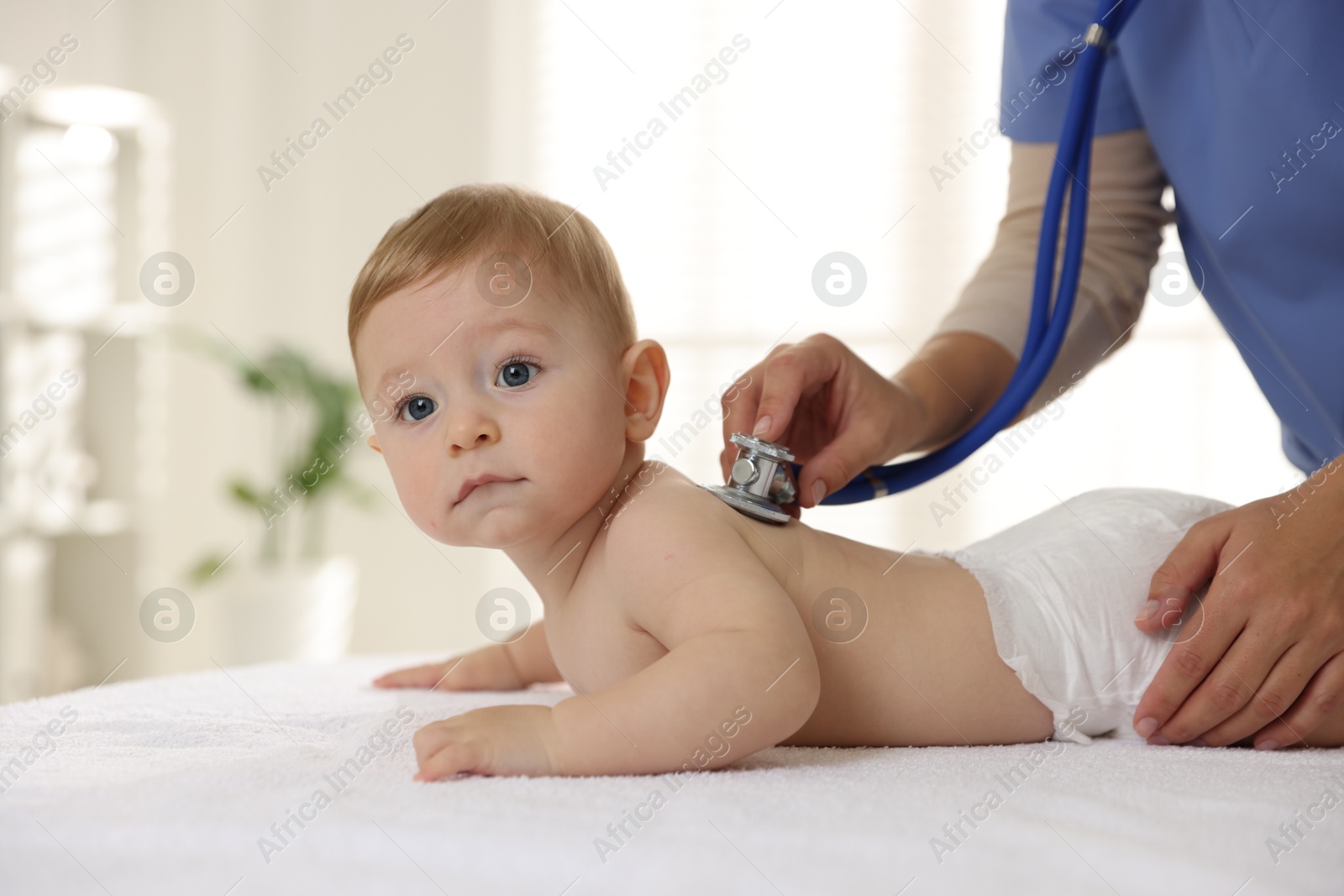 Photo of Pediatrician examining little child with stethoscope in clinic, closeup. Checking baby's health