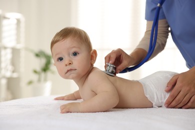 Pediatrician examining little child with stethoscope in clinic, closeup. Checking baby's health