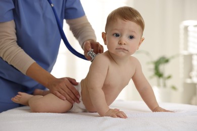 Pediatrician examining little child with stethoscope in clinic, closeup. Checking baby's health