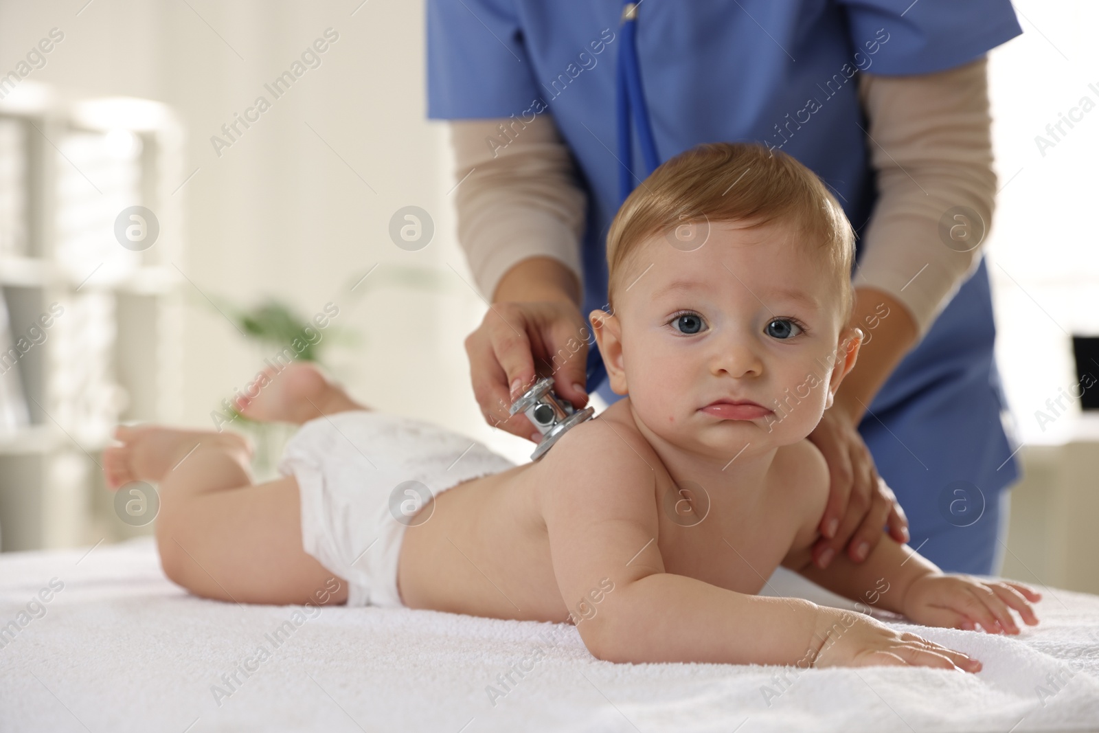 Photo of Pediatrician examining little child with stethoscope in clinic, closeup. Checking baby's health