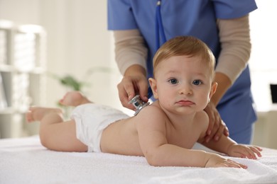 Photo of Pediatrician examining little child with stethoscope in clinic, closeup. Checking baby's health