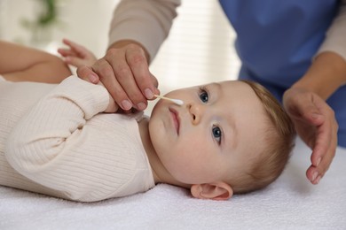 Photo of Pediatrician with cotton swab and cute little baby in clinic, closeup