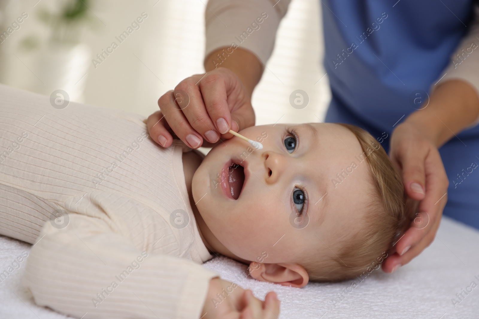 Photo of Pediatrician with cotton swab and cute little baby in clinic, closeup