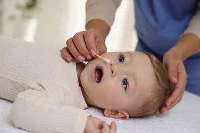 Pediatrician with cotton swab and cute little baby in clinic, closeup