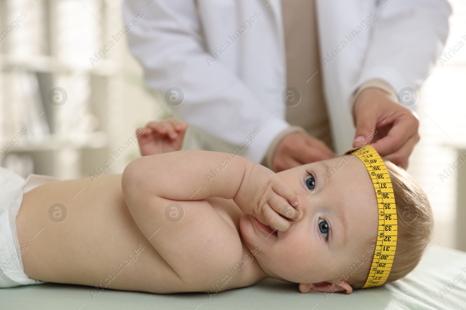 Photo of Pediatrician measuring little baby's head in clinic, closeup