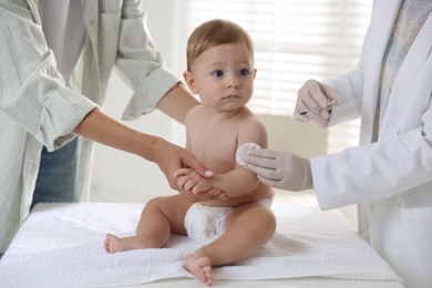 Pediatrician vaccinating little baby in clinic, closeup