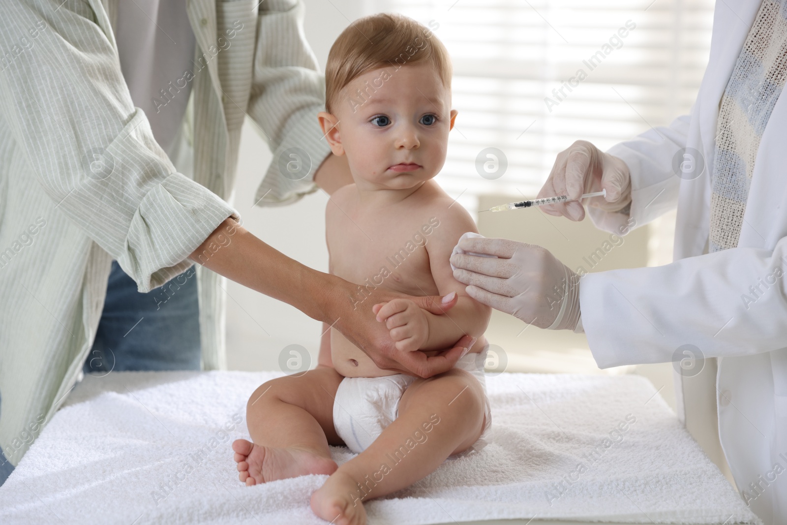 Photo of Pediatrician vaccinating little baby in clinic, closeup