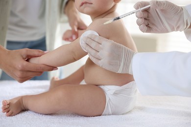 Pediatrician vaccinating little baby in clinic, closeup