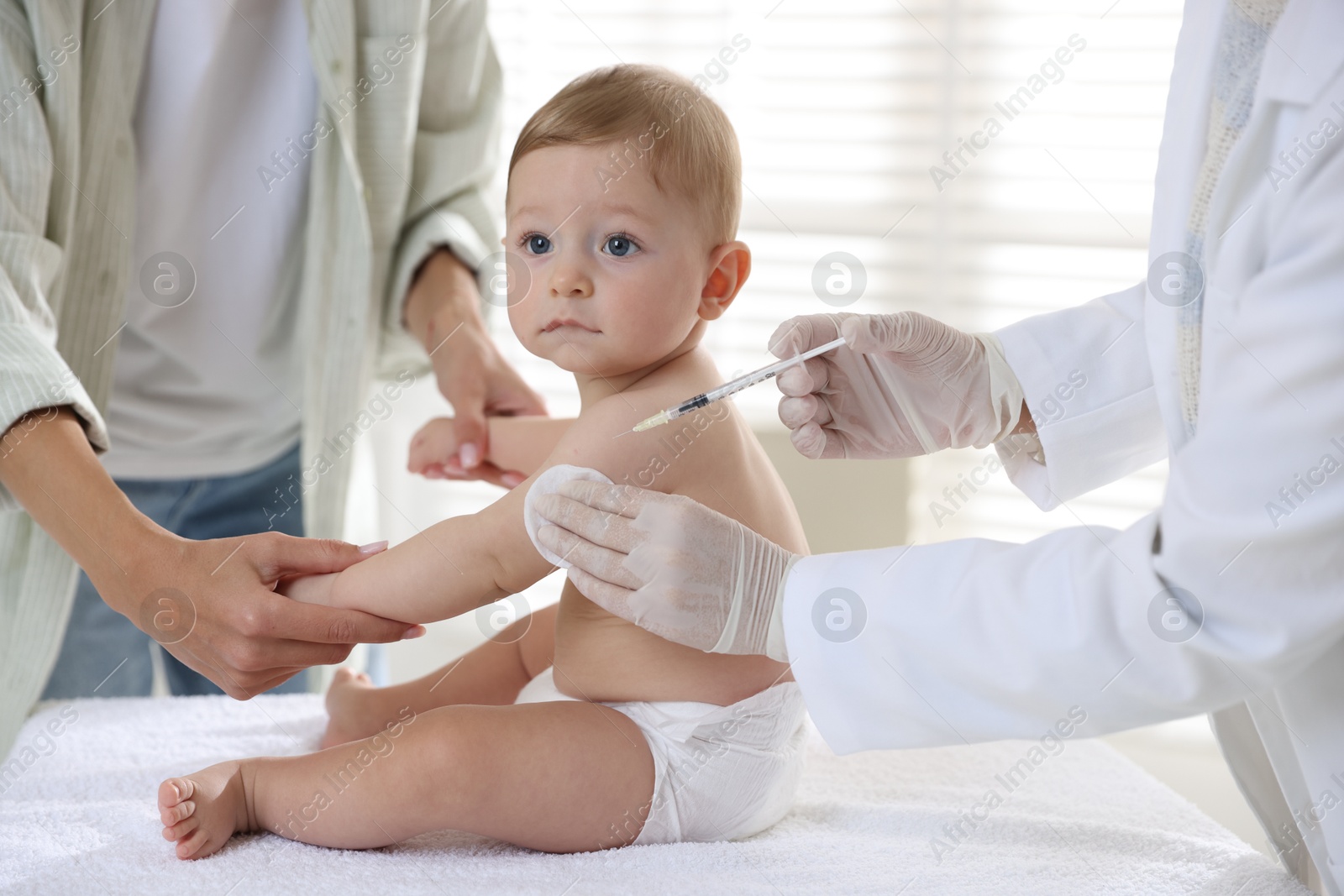 Photo of Pediatrician vaccinating little baby in clinic, closeup