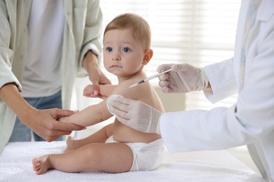 Pediatrician vaccinating little baby in clinic, closeup