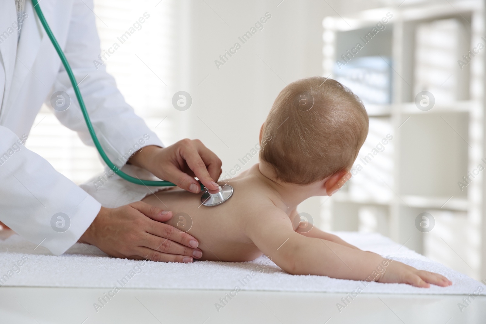 Photo of Pediatrician examining little child with stethoscope in clinic, closeup. Checking baby's health