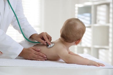 Photo of Pediatrician examining little child with stethoscope in clinic, closeup. Checking baby's health