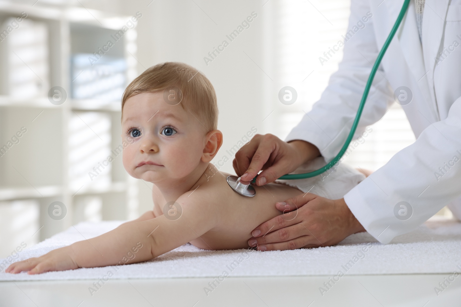 Photo of Pediatrician examining little child with stethoscope in clinic, closeup. Checking baby's health