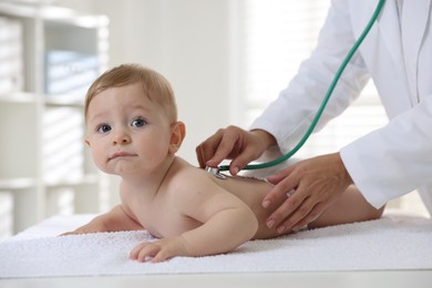 Photo of Pediatrician examining little child with stethoscope in clinic, closeup. Checking baby's health