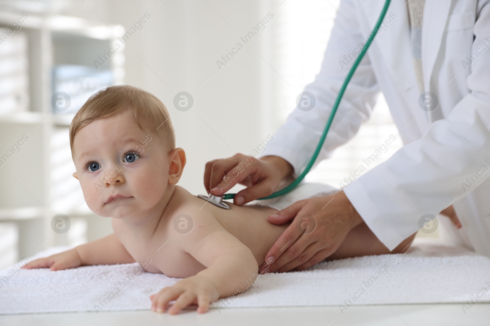 Photo of Pediatrician examining little child with stethoscope in clinic, closeup. Checking baby's health