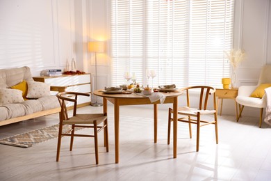 Stylish table setting with beautiful dishware and autumn decor in dining room