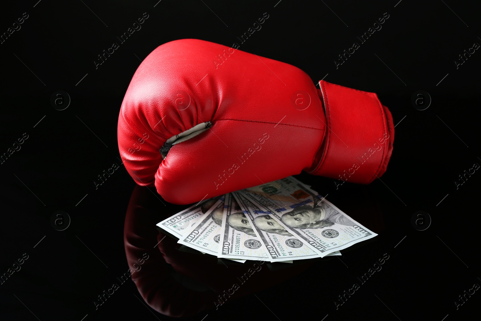 Photo of Red boxing glove and dollar banknotes on black mirror surface