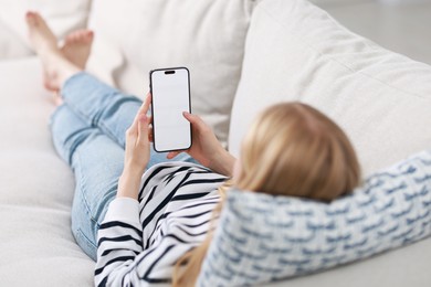 Photo of Woman using smartphone on sofa at home