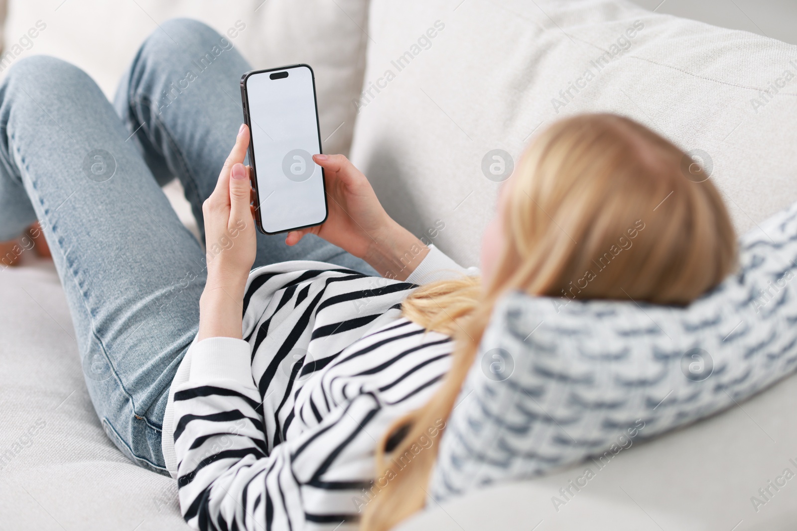 Photo of Woman using smartphone on sofa at home