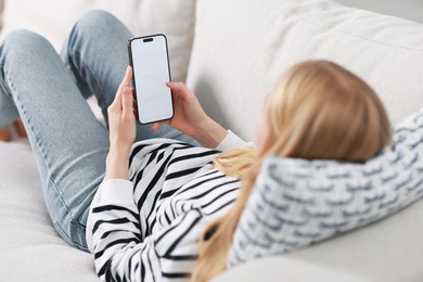 Woman using smartphone on sofa at home