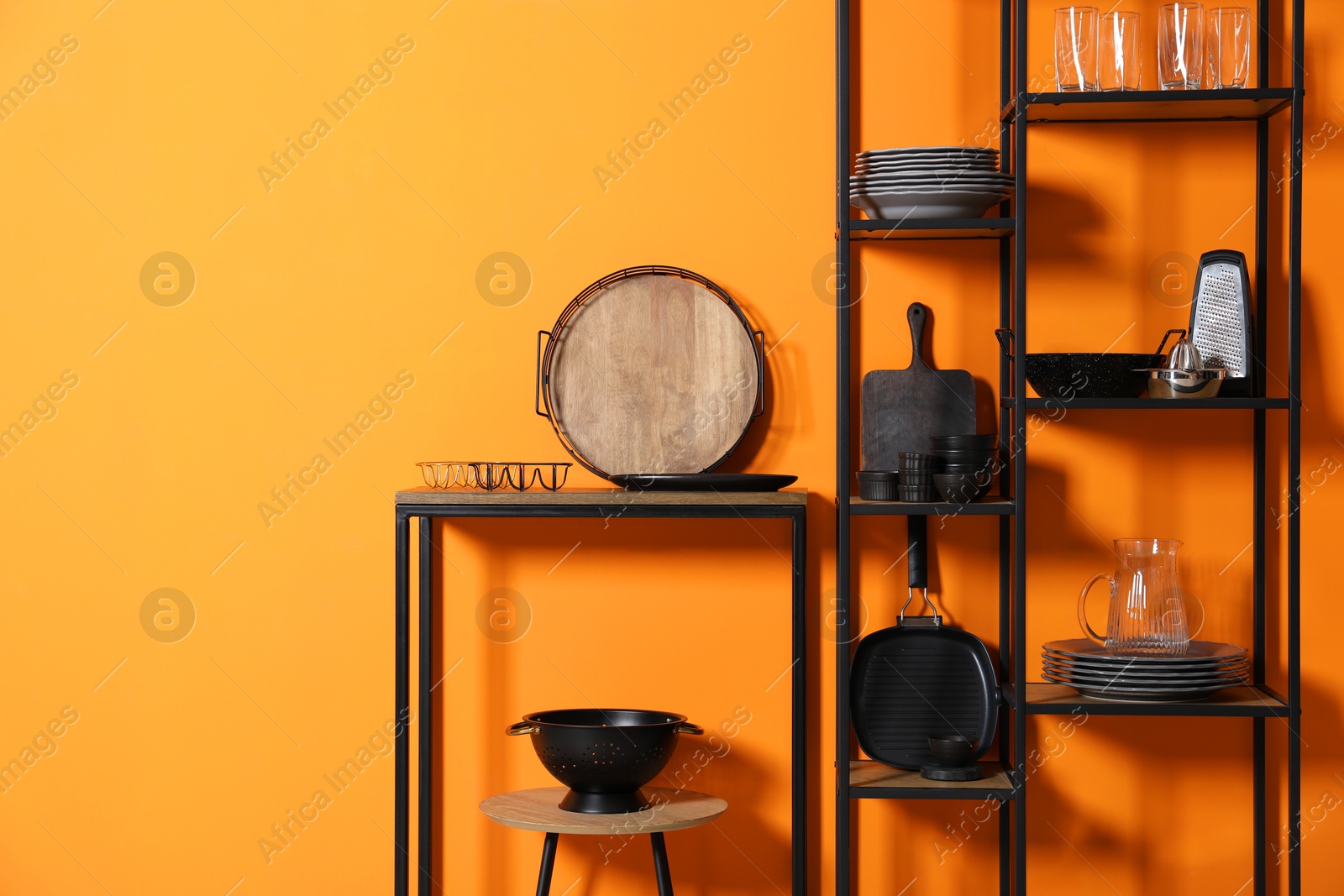 Photo of Storage stands with kitchenware near orange wall indoors