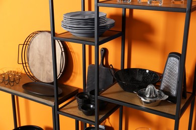 Photo of Storage stands with kitchenware near orange wall indoors