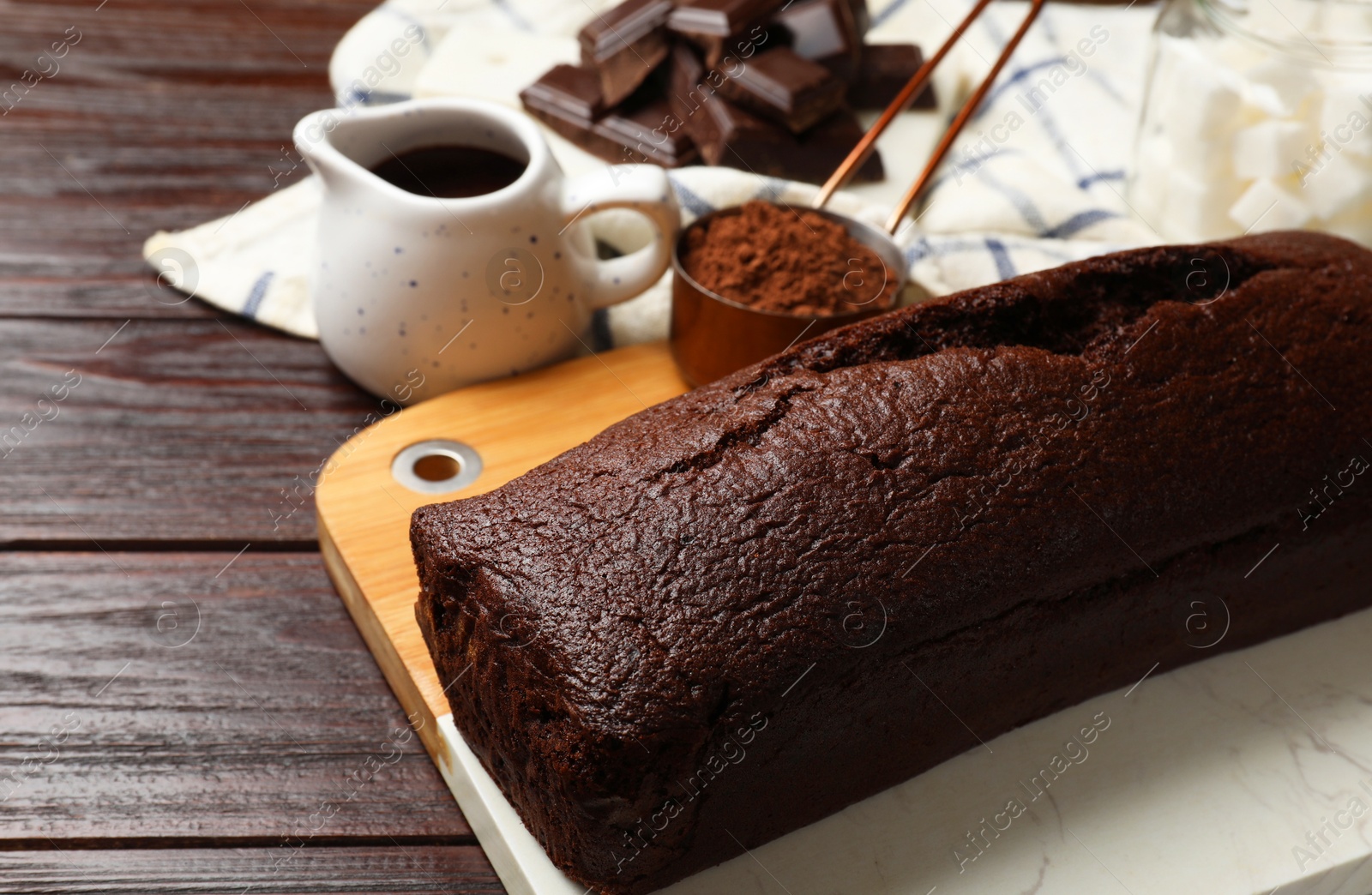 Photo of Tasty chocolate sponge cake and ingredients on wooden table, closeup