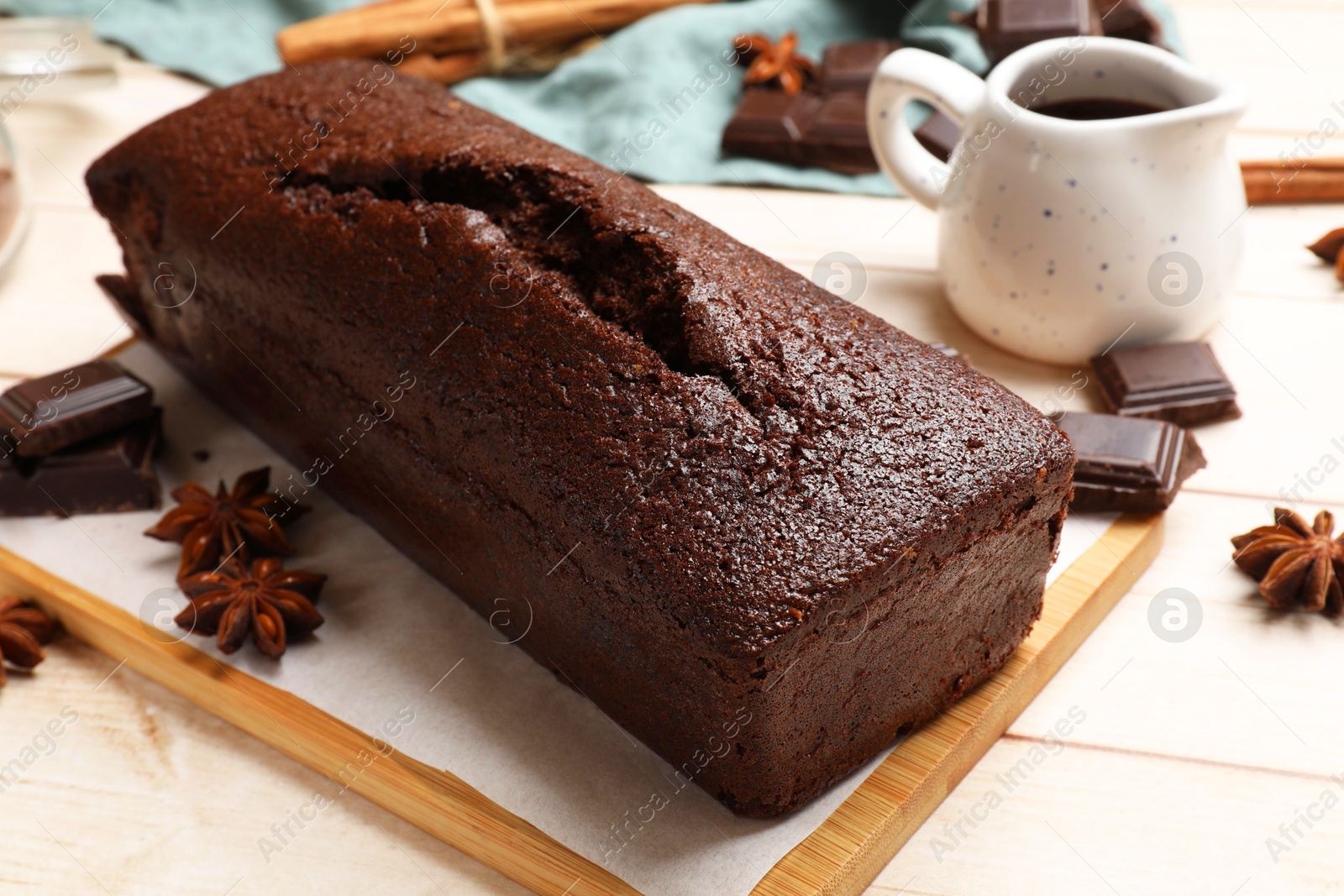 Photo of Tasty chocolate sponge cake and ingredients on white wooden table, closeup