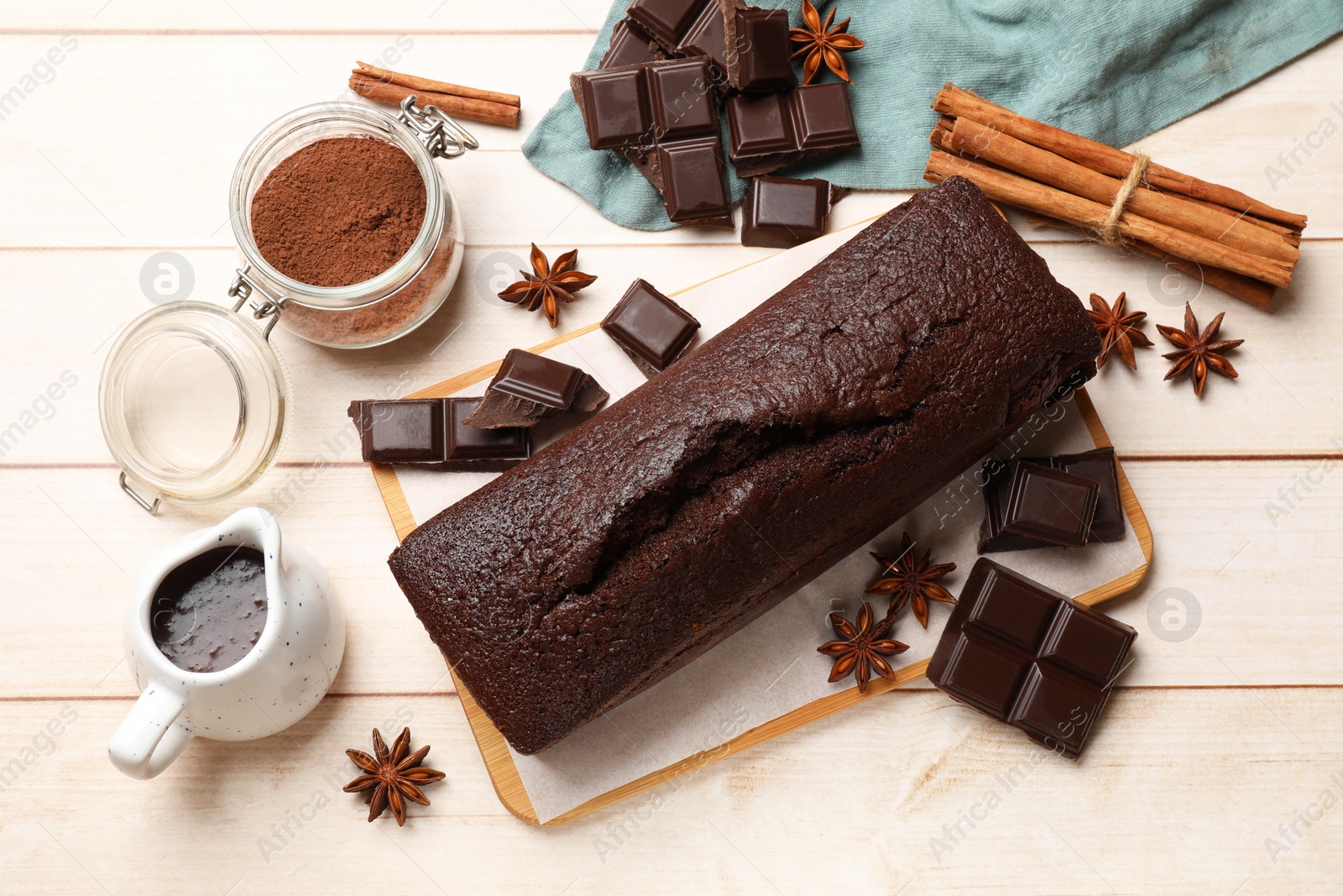 Photo of Tasty chocolate sponge cake and ingredients on white wooden table, flat lay