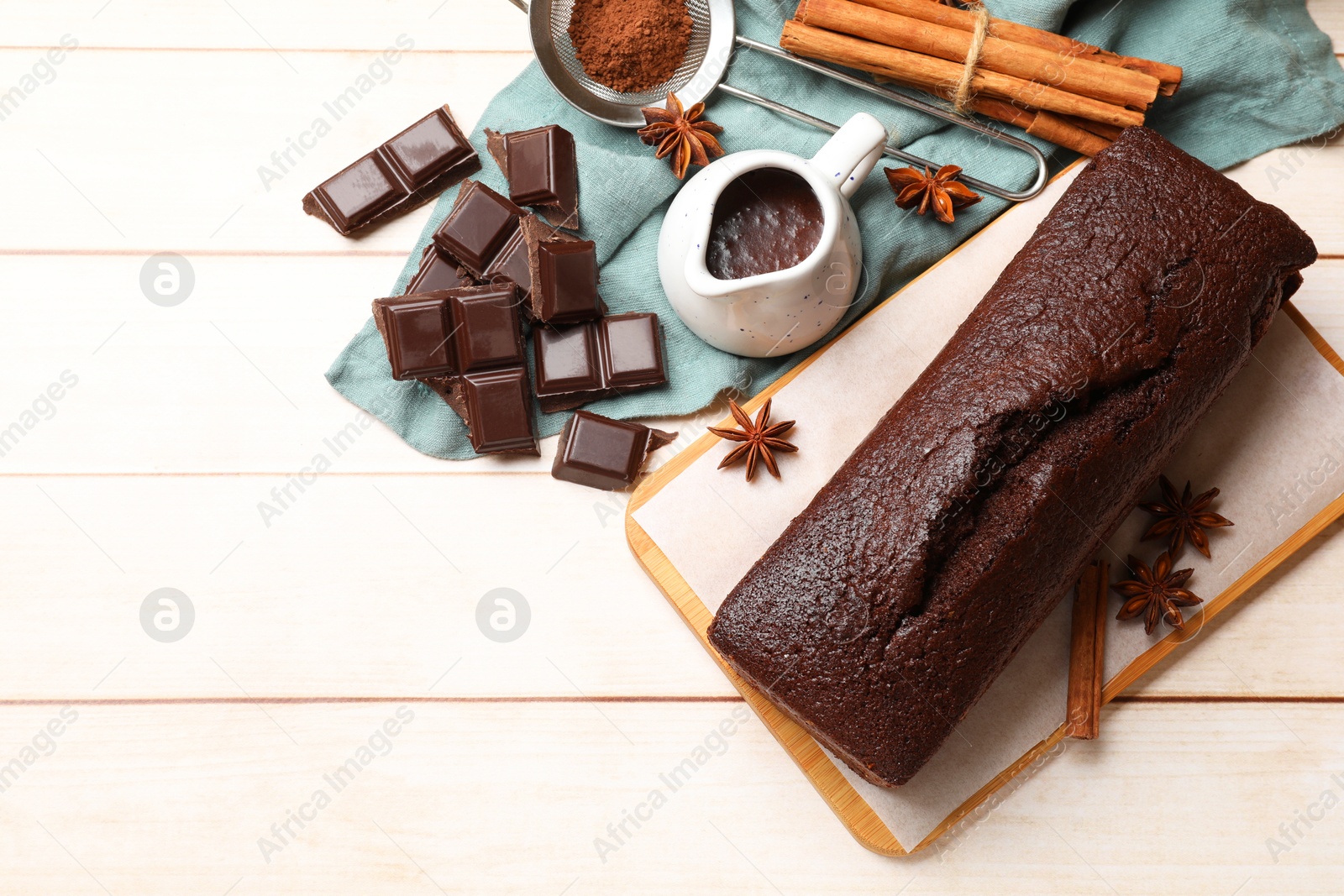 Photo of Tasty chocolate sponge cake and ingredients on white wooden table, flat lay. Space for text