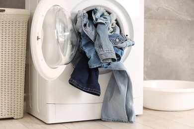 Washing machine with dirty jeans and other denim clothes indoors