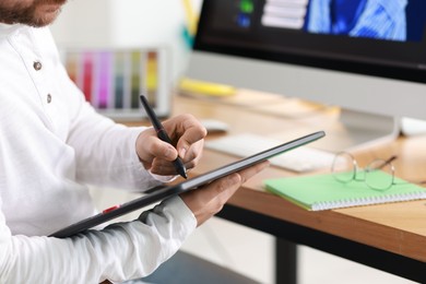 Photo of Designer working with tablet in office, closeup