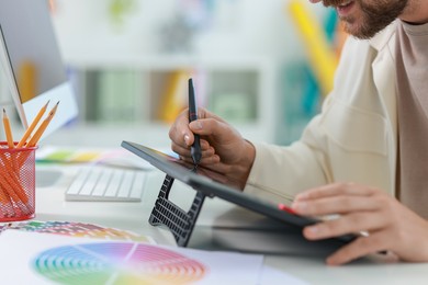 Designer working with tablet at table in office, closeup