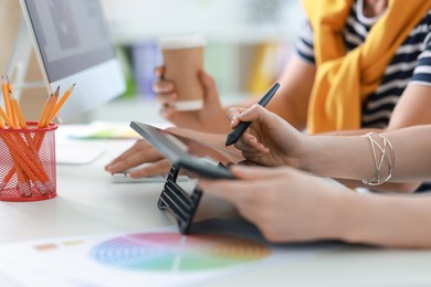 Photo of Designers with tablet working together at table in office, closeup