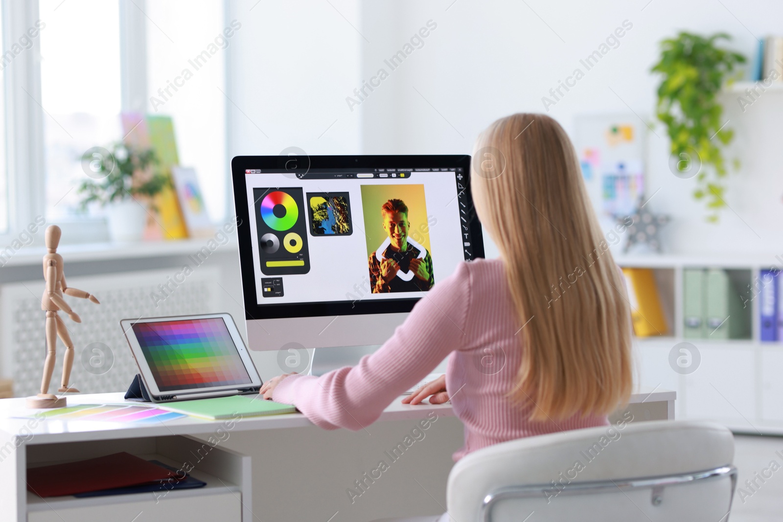 Photo of Graphic designer working with computer at table in office, back view