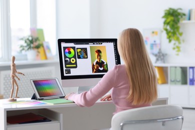 Photo of Graphic designer working with computer at table in office, back view