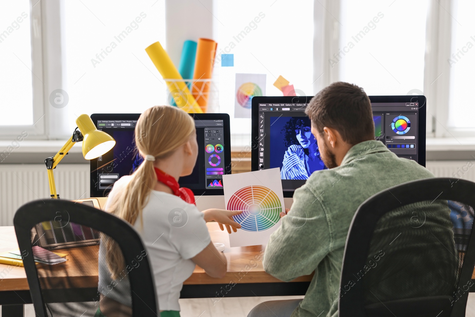 Photo of Designers with color palette working together at table in office, back view